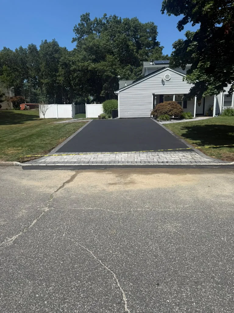 Newly paved asphalt driveway with light paver apron and Belgian block border curbs in Fairfield County CT