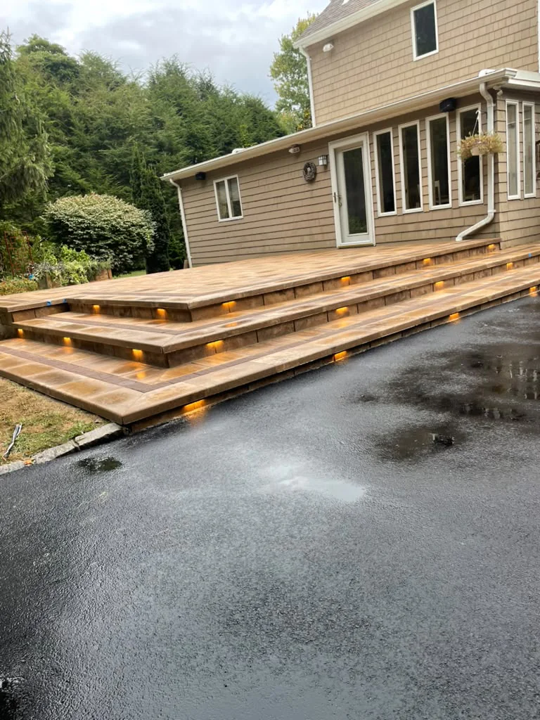 Tiered raised paver patio with built-in warm LED step riser lights installed by StoneForge Paving & Masonry in Connecticut