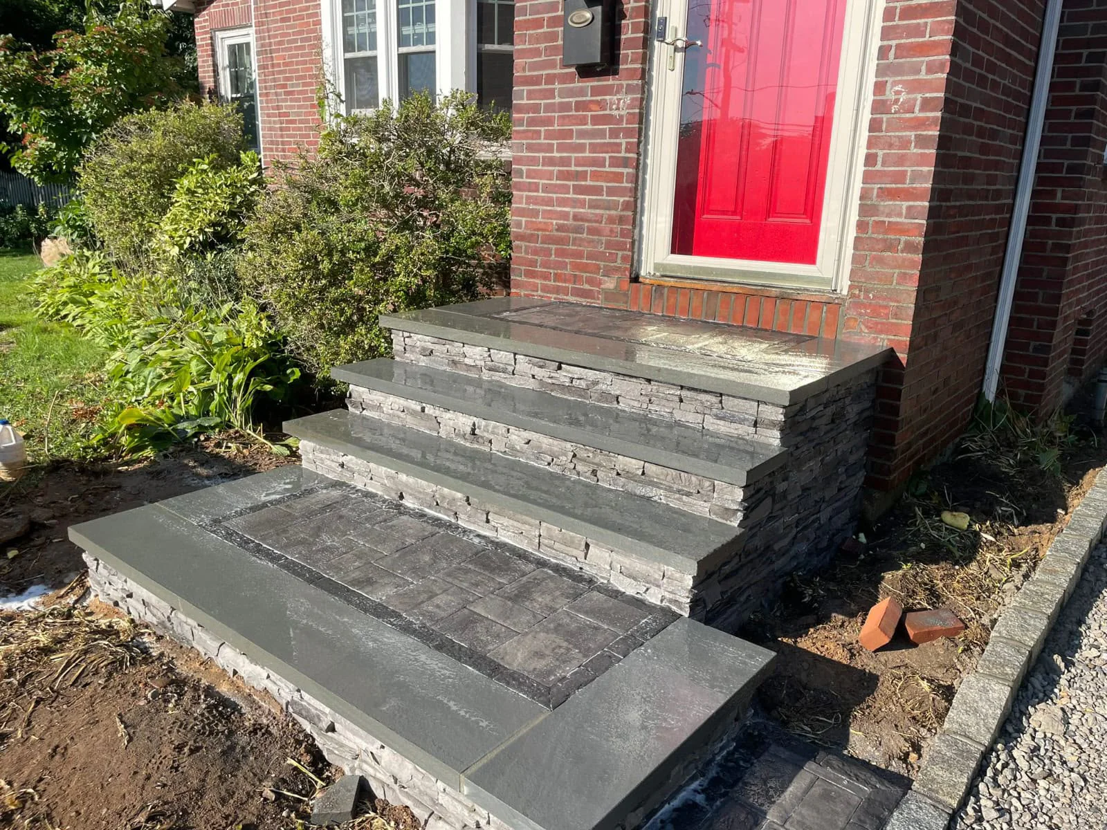 Custom masonry front entrance steps and stoop with natural bluestone treads and stacked stone veneer risers in Connecticut